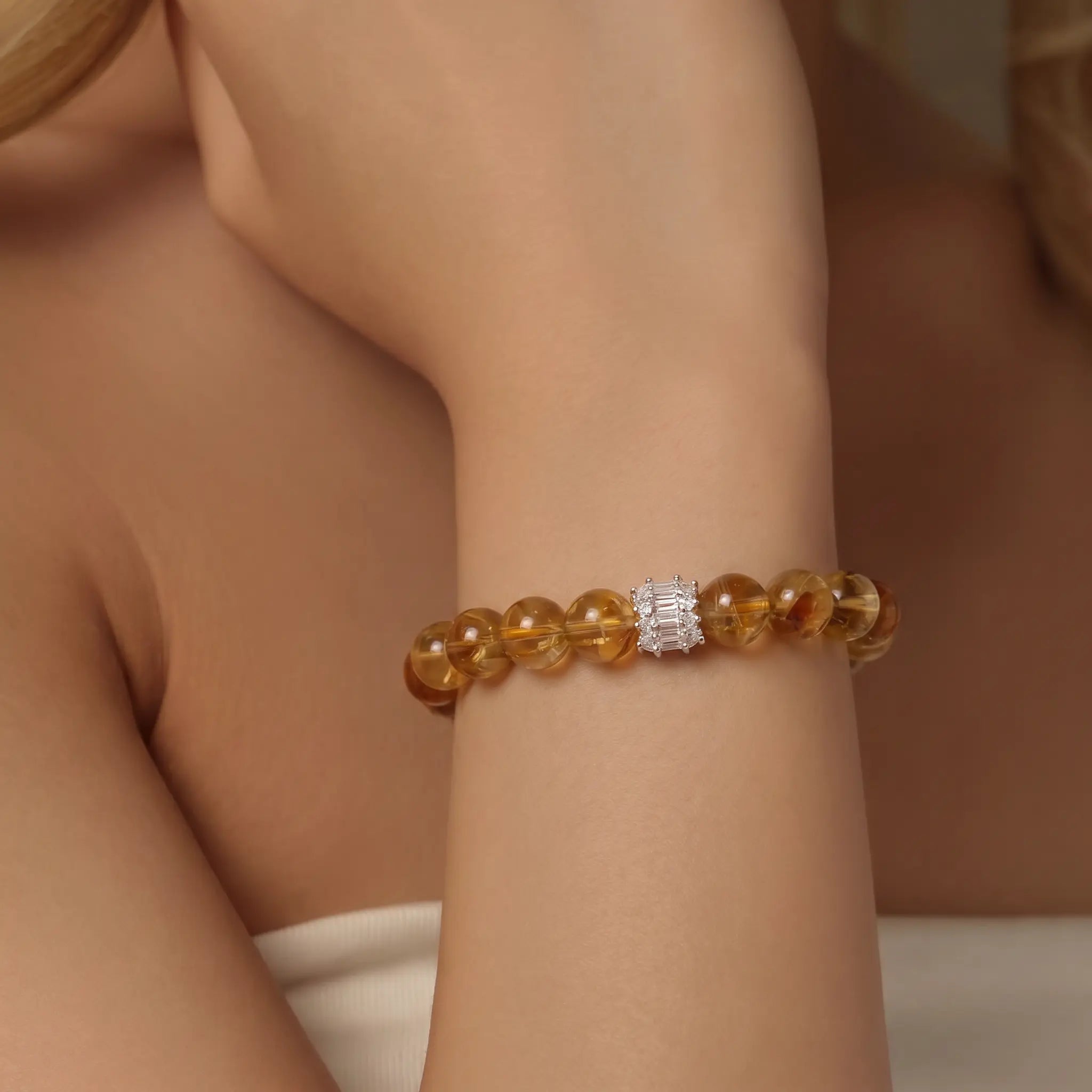 Close-up portrait view of a woman wrist elegantly wearing the Solar Radiance Citrine Bracelet with a silver gemstone centerpiece.