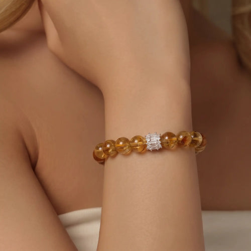 Close-up portrait view of a woman wrist elegantly wearing the Solar Radiance Citrine Bracelet with a silver gemstone centerpiece.
