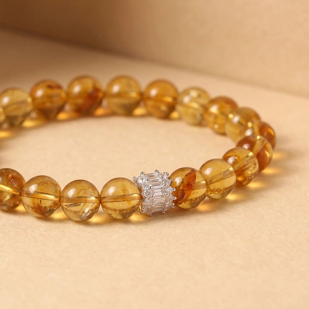 Macro shot of the Solar Radiance Citrine Bracelet resting flat over a warm, solid background with a focused view on the silver centerpiece.