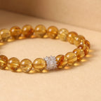 Macro shot of the Solar Radiance Citrine Bracelet resting flat over a warm, solid background with a focused view on the silver centerpiece.