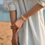 Diagonal rear view extending to the left elbow while the right hand grasps the wrist showcasing a citrine crystal bracelet.