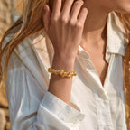 Cropped upper body shot to the earlobe showing a woman right forearm with a hand touching the earlobe to display a crystal bracelet.