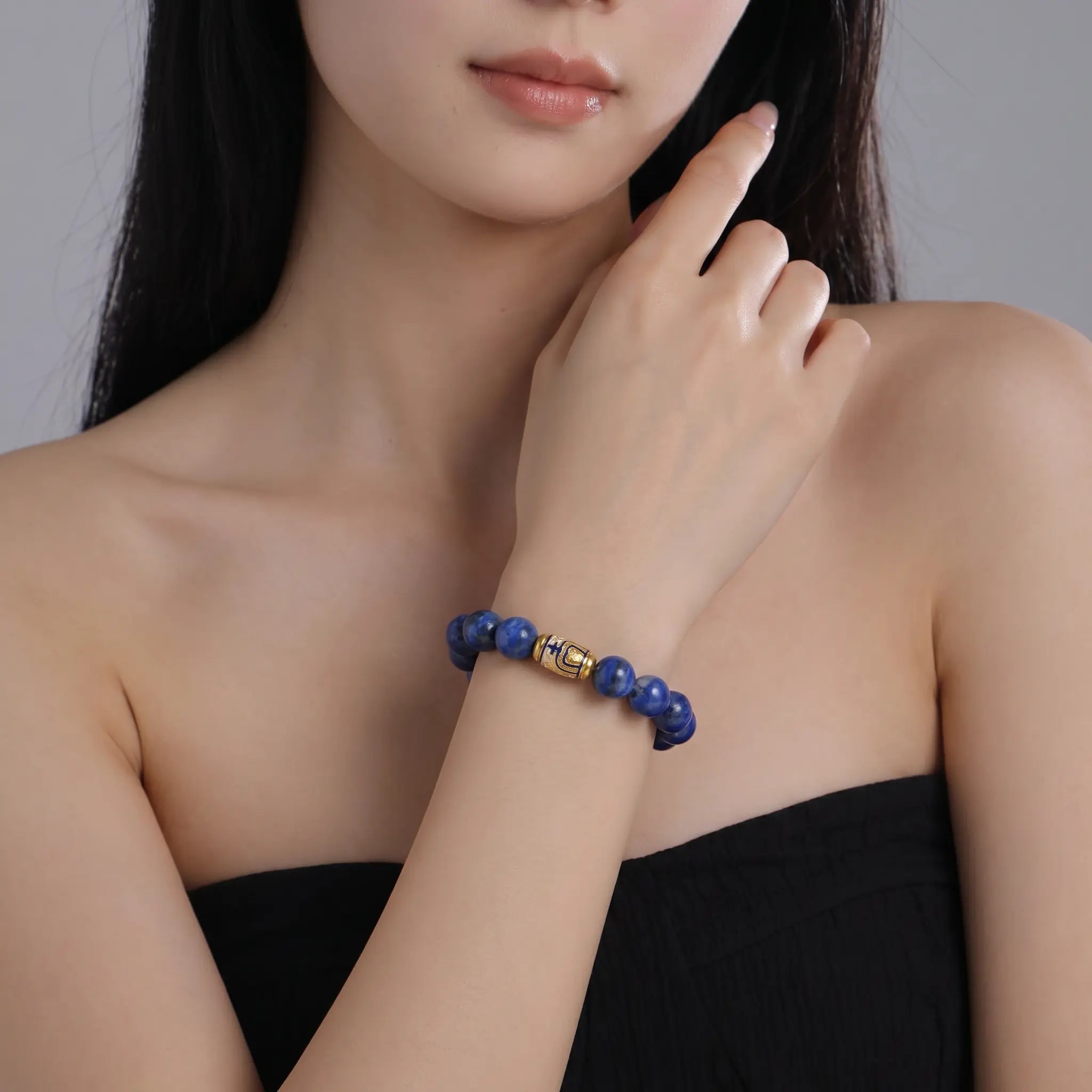 Front portrait view up to the chin showing an elegant lady wearing the Tranquil Lapis Bracelet against her black strapless top.