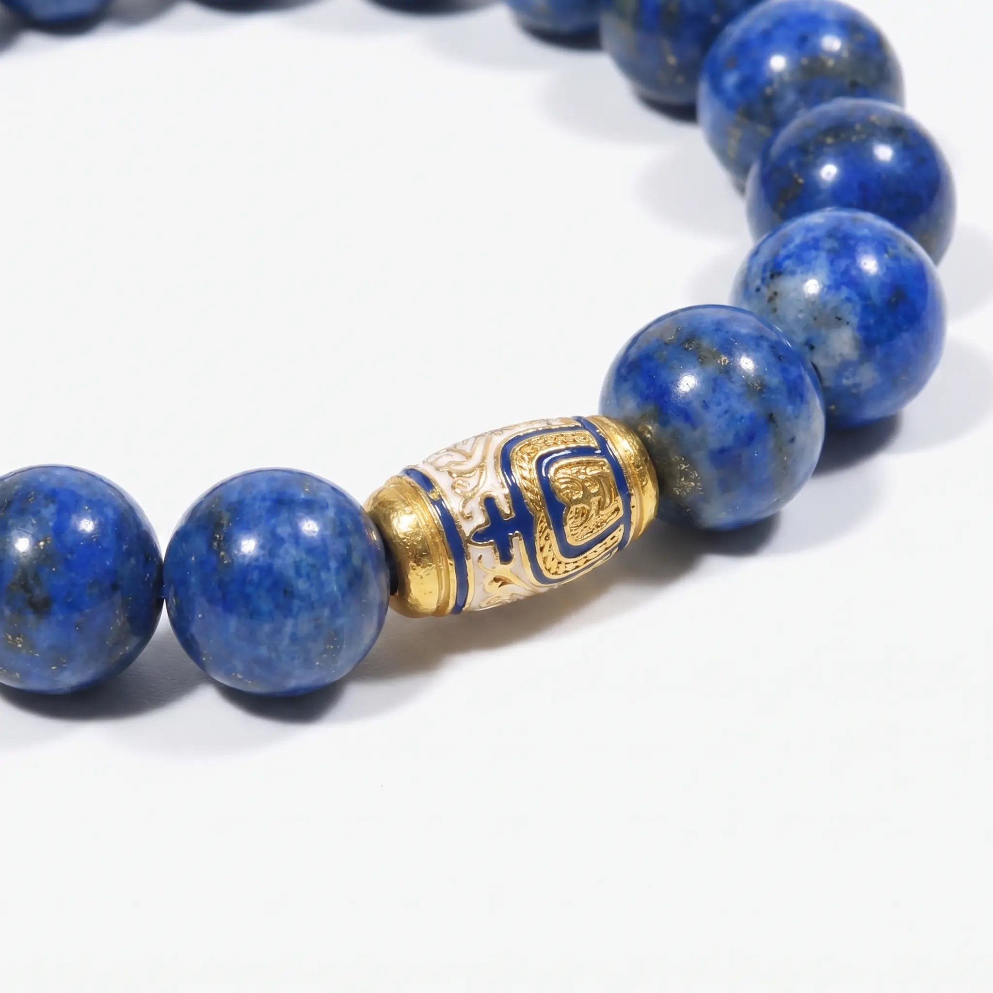Macro shot of the Tranquil Lapis Bracelet focusing on the natural textures of deep blue lapis lazuli beads and a gold enameled centerpiece.