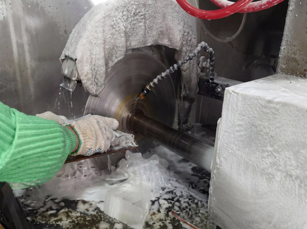 Cutting raw gemstone material with a precision blade during the handmade jewelry crafting process.